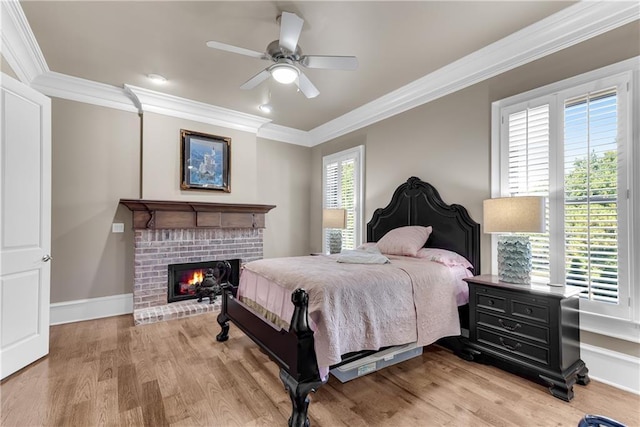 bedroom featuring a fireplace, crown molding, light wood-style flooring, and baseboards