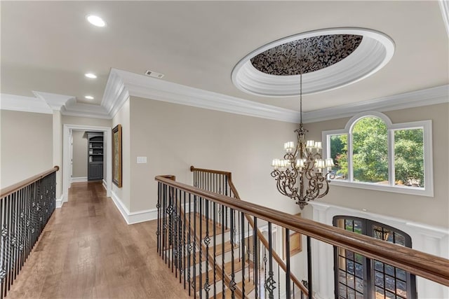 hall featuring a chandelier, recessed lighting, wood finished floors, an upstairs landing, and ornamental molding