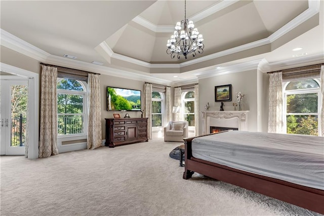 carpeted bedroom featuring access to exterior, a raised ceiling, a lit fireplace, and an inviting chandelier