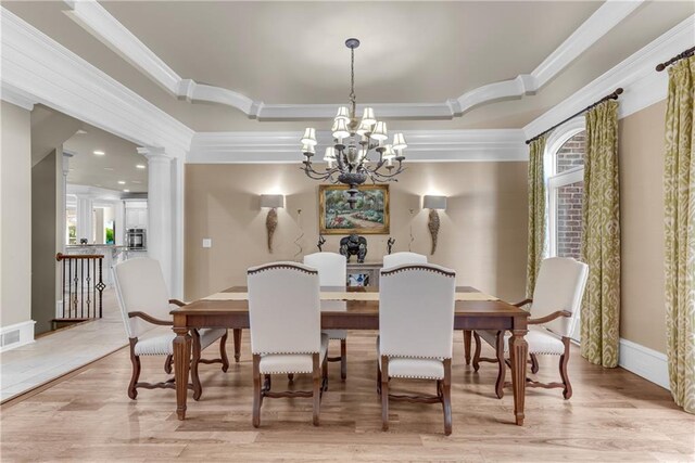 dining space featuring ornamental molding, a notable chandelier, decorative columns, and light hardwood / wood-style floors