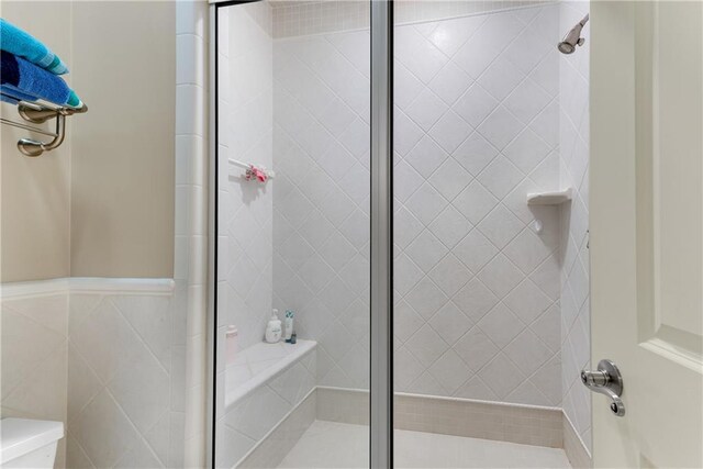 bathroom featuring toilet and a shower with shower door