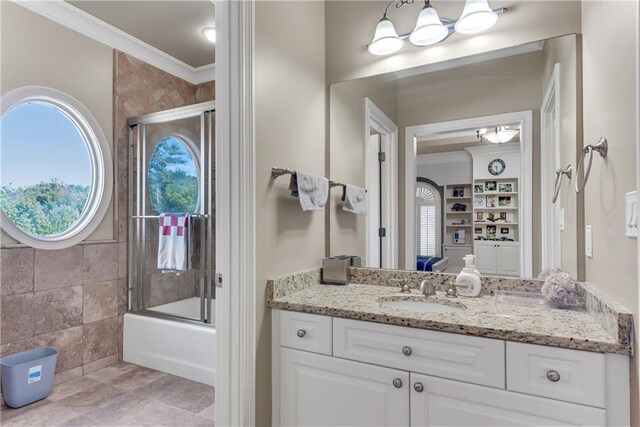 bathroom with ornamental molding, vanity, combined bath / shower with glass door, and tile walls