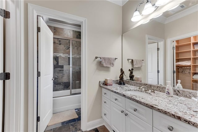 full bathroom with baseboards, shower / bath combination with glass door, stone finish floor, crown molding, and vanity