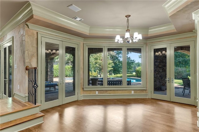 unfurnished sunroom with a notable chandelier, visible vents, a wealth of natural light, and french doors