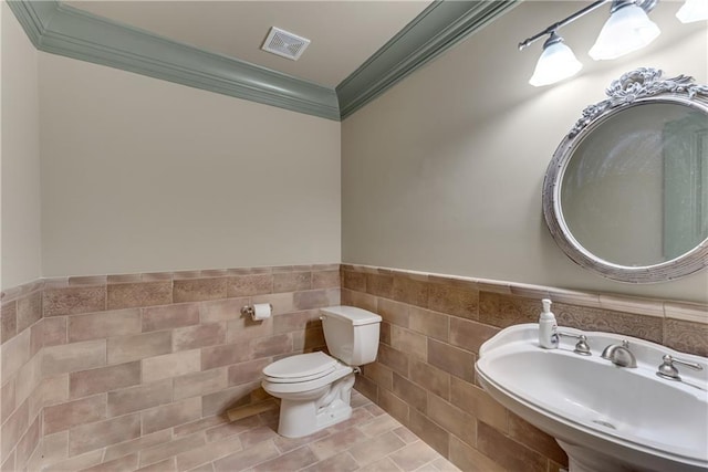 bathroom featuring crown molding, tile walls, toilet, sink, and tile patterned floors