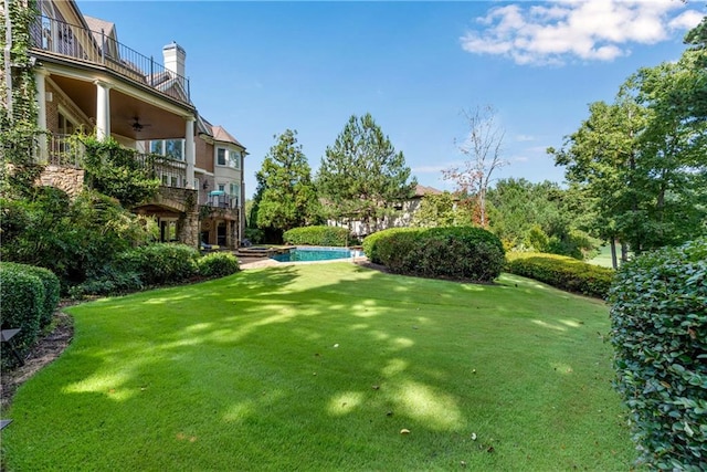 view of yard with a balcony and ceiling fan