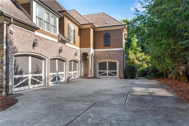 view of front of property featuring driveway, an attached garage, and brick siding