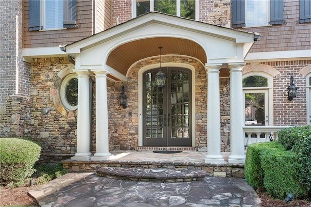 doorway to property featuring covered porch, french doors, and brick siding