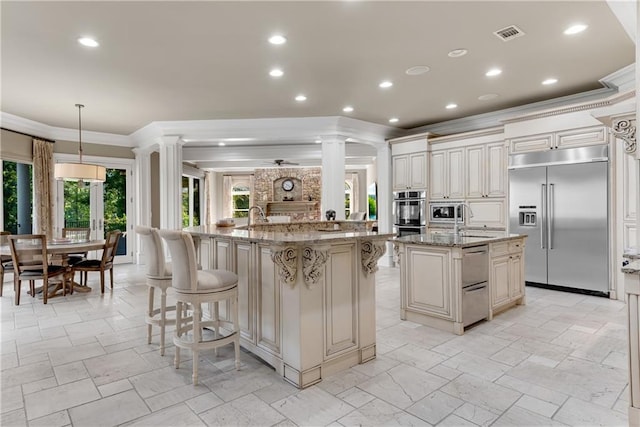 kitchen featuring built in appliances, ornate columns, a spacious island, a warming drawer, and crown molding