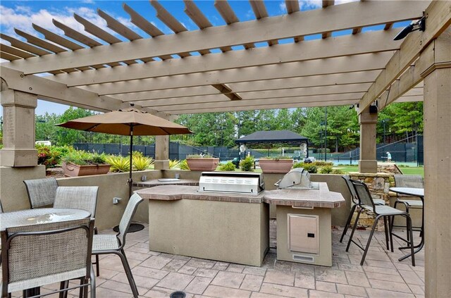 view of patio with exterior kitchen, a pergola, and area for grilling