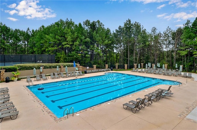 community pool with a patio area and fence