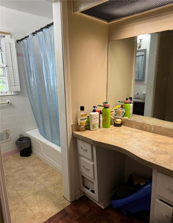 bathroom featuring shower / bath combination with curtain, tile patterned flooring, vanity, and tile walls