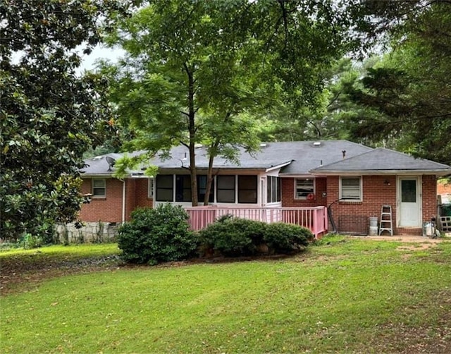 rear view of house with brick siding and a yard