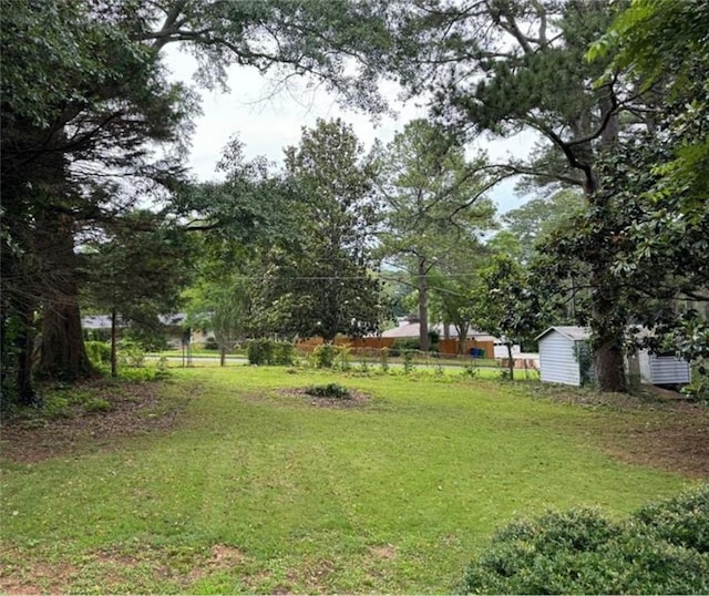 view of yard featuring an outdoor structure, fence, and a shed