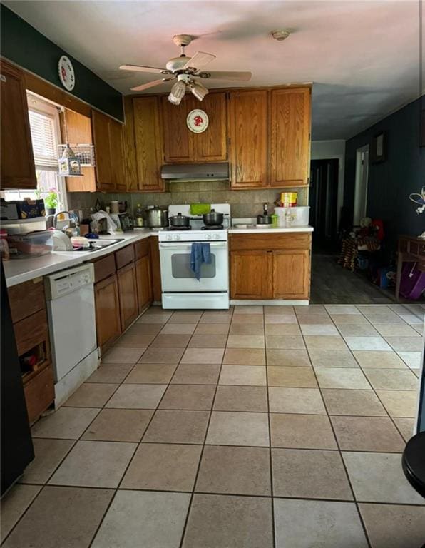 kitchen featuring light countertops, white appliances, brown cabinets, and under cabinet range hood