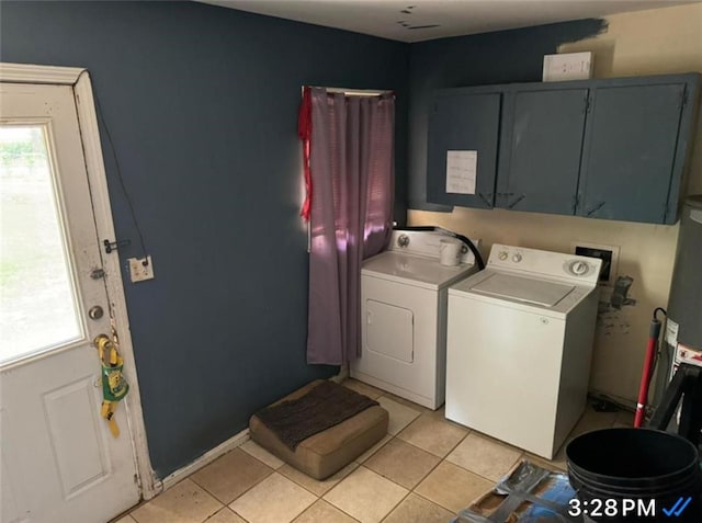 clothes washing area featuring light tile patterned flooring, cabinet space, and separate washer and dryer