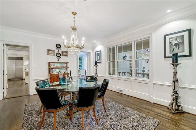 dining room with a chandelier, dark wood-style flooring, ornamental molding, a decorative wall, and a wainscoted wall