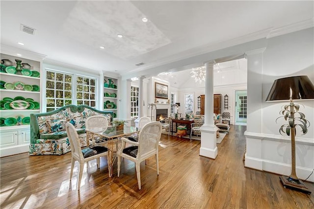 dining room featuring ornamental molding, ornate columns, a lit fireplace, wood finished floors, and recessed lighting