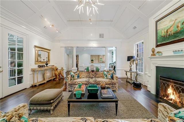 living area with vaulted ceiling, a lit fireplace, wood finished floors, crown molding, and a chandelier