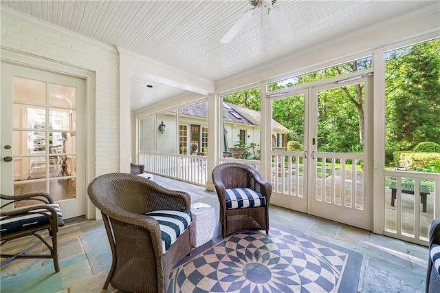 sunroom / solarium with stone tile floors, french doors, a ceiling fan, and crown molding