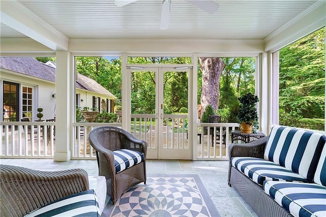 sunroom with stone tile floors, a ceiling fan, ornamental molding, and french doors