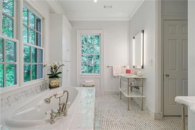 bathroom featuring a bath, baseboards, ornamental molding, and a sink