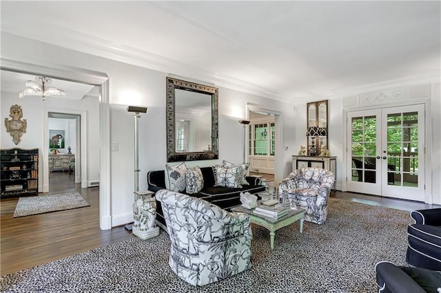 living room featuring ornamental molding, wood finished floors, french doors, and a chandelier