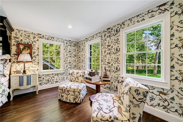 living area featuring crown molding, wood finished floors, wallpapered walls, and baseboards