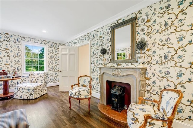 sitting room featuring wallpapered walls, wood finished floors, crown molding, and baseboards
