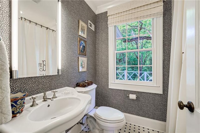 full bath featuring healthy amount of natural light, toilet, a sink, and baseboards