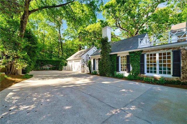 view of front of house featuring a chimney, a garage, and concrete driveway