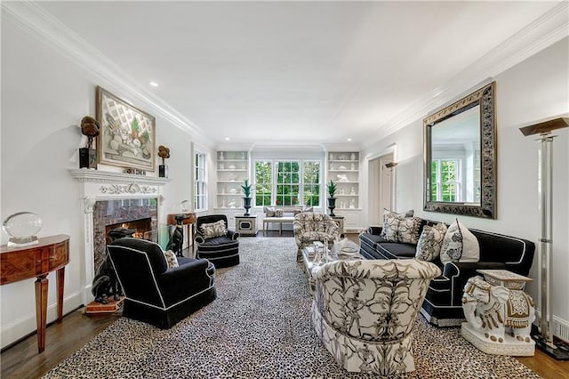 living area featuring wood finished floors, crown molding, a premium fireplace, built in shelves, and baseboards