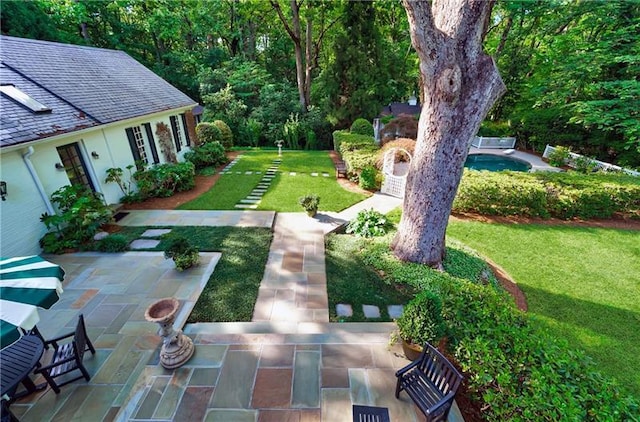 view of grassy yard with a patio area and an outdoor pool