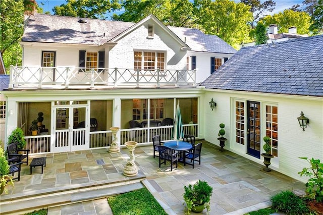 rear view of property featuring a balcony, a patio area, and french doors