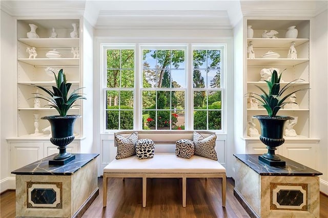 living area with crown molding, wood finished floors, plenty of natural light, and built in features