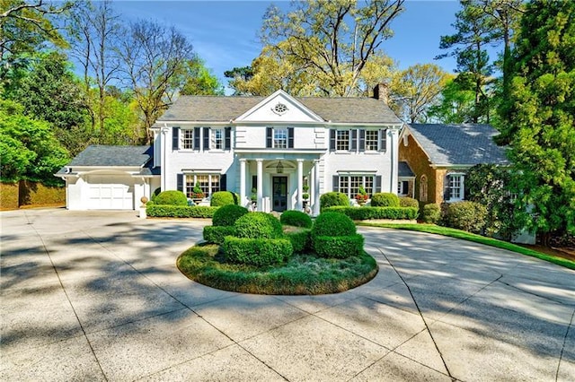 georgian-style home featuring curved driveway, a chimney, and an attached garage