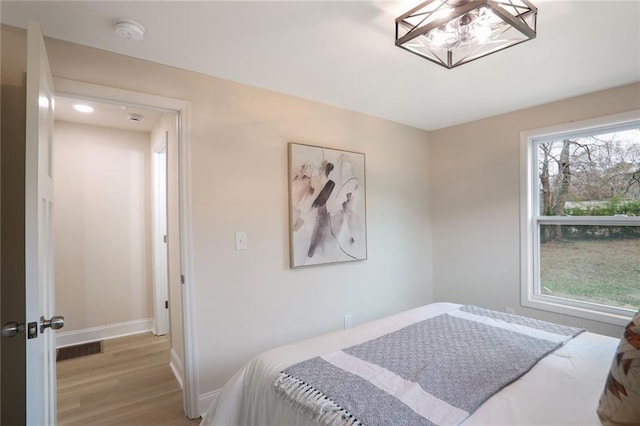 bedroom featuring visible vents, baseboards, and wood finished floors