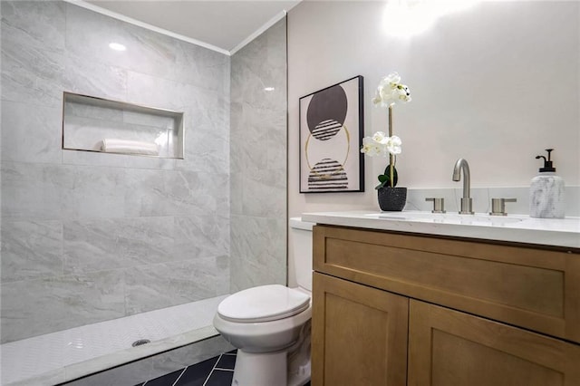 full bathroom featuring vanity, toilet, a tile shower, and ornamental molding