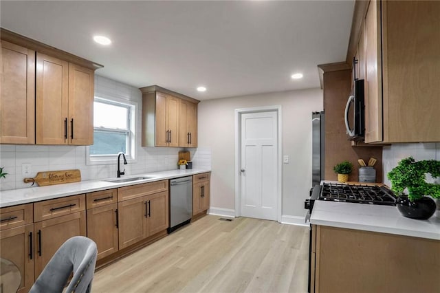 kitchen with baseboards, decorative backsplash, light wood-style flooring, stainless steel appliances, and a sink