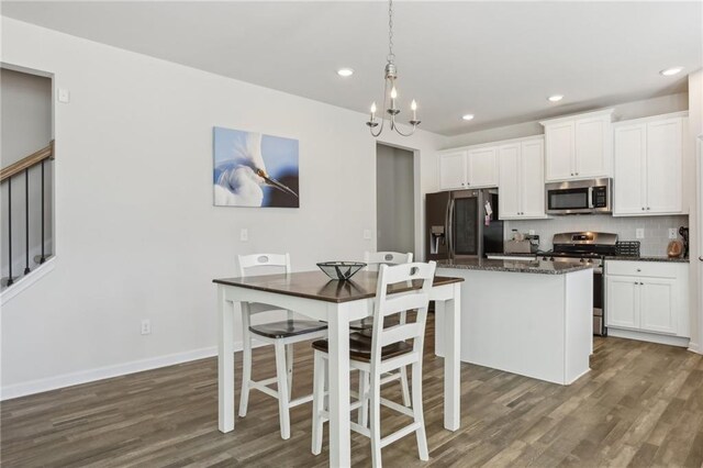 kitchen featuring dark wood-style floors, stainless steel appliances, decorative backsplash, white cabinets, and a notable chandelier