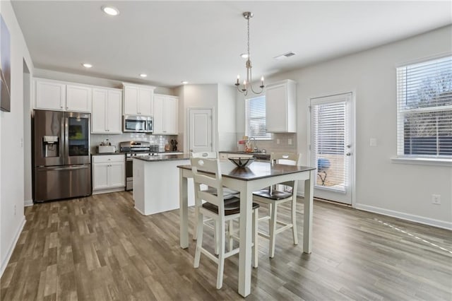 kitchen with dark countertops, backsplash, dark wood finished floors, white cabinets, and stainless steel appliances