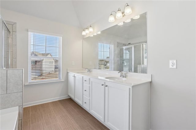 full bath featuring vaulted ceiling, double vanity, a shower with door, and a sink