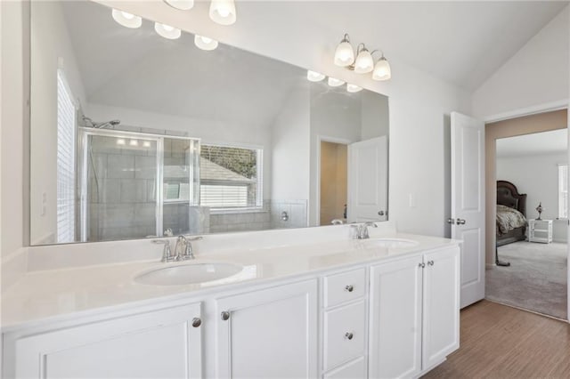 full bath with double vanity, a stall shower, lofted ceiling, and a sink
