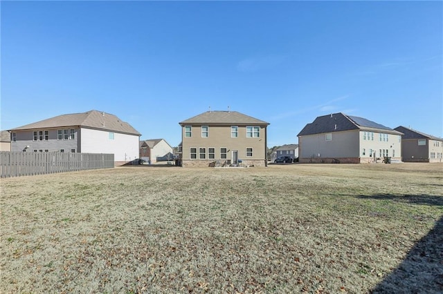 rear view of property with a residential view, a lawn, and fence