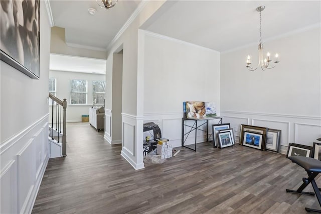 foyer entrance featuring dark wood-type flooring, stairway, ornamental molding, a notable chandelier, and a decorative wall