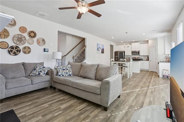 living area with stairway, recessed lighting, light wood-style floors, and ceiling fan