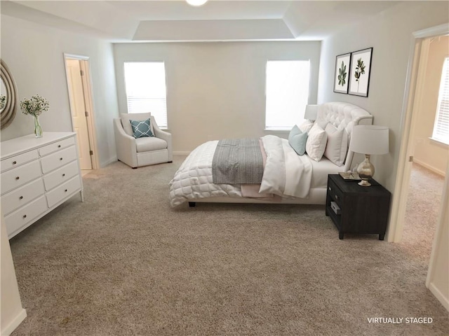 carpeted bedroom with multiple windows and a tray ceiling