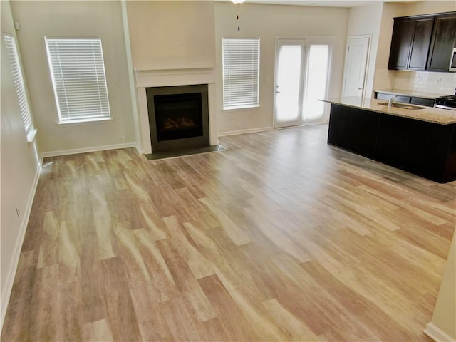 unfurnished living room featuring light hardwood / wood-style floors, sink, and ceiling fan