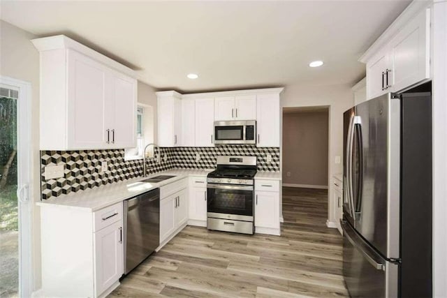 kitchen featuring white cabinets, light hardwood / wood-style floors, appliances with stainless steel finishes, and sink