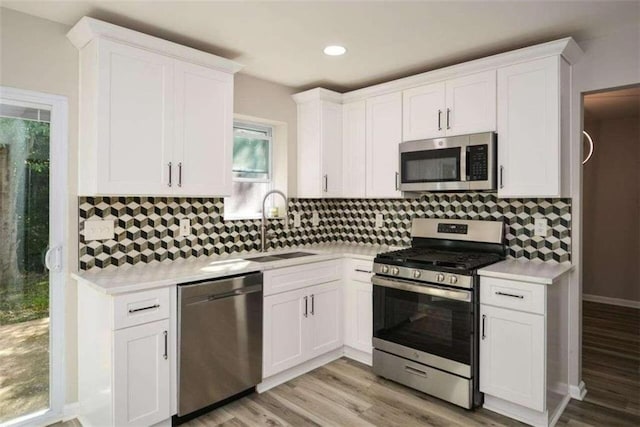 kitchen featuring white cabinets, stainless steel appliances, sink, and light hardwood / wood-style flooring